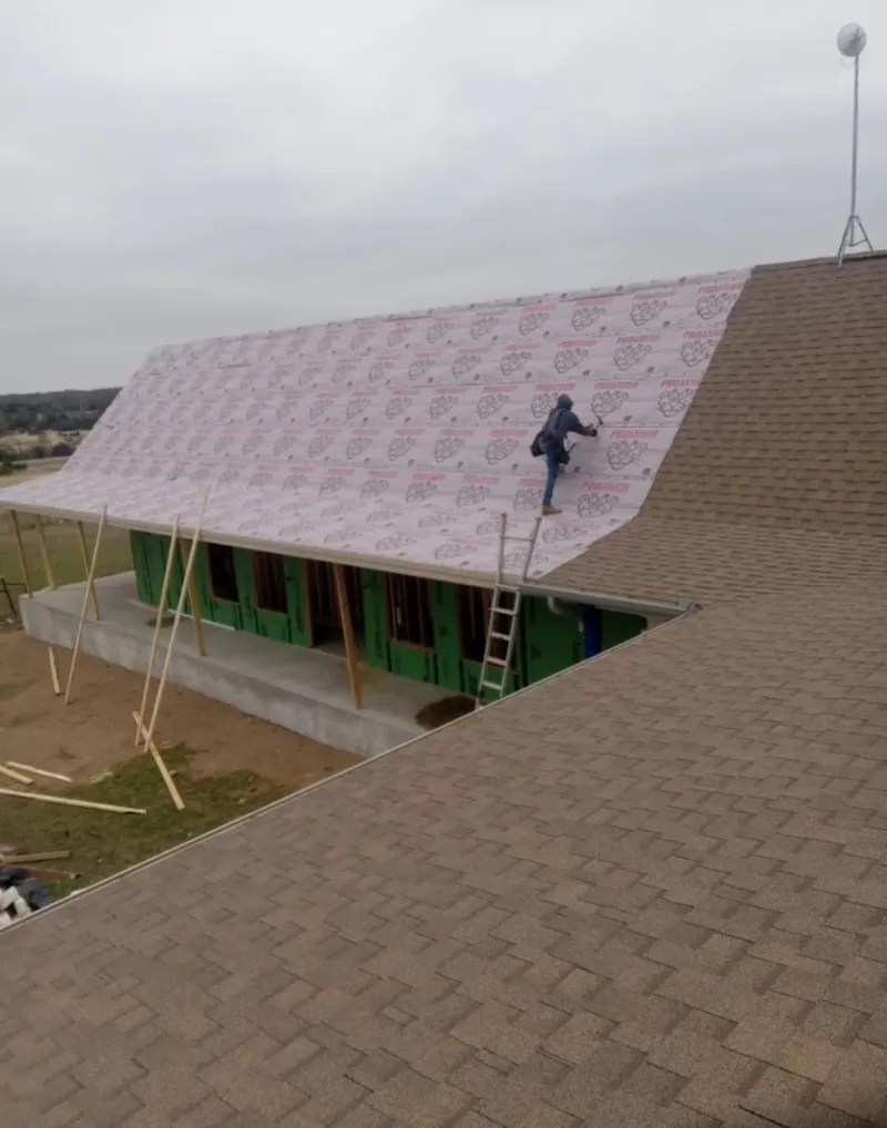 Worker preparing underlayment for a metal roof installation in Brownsville